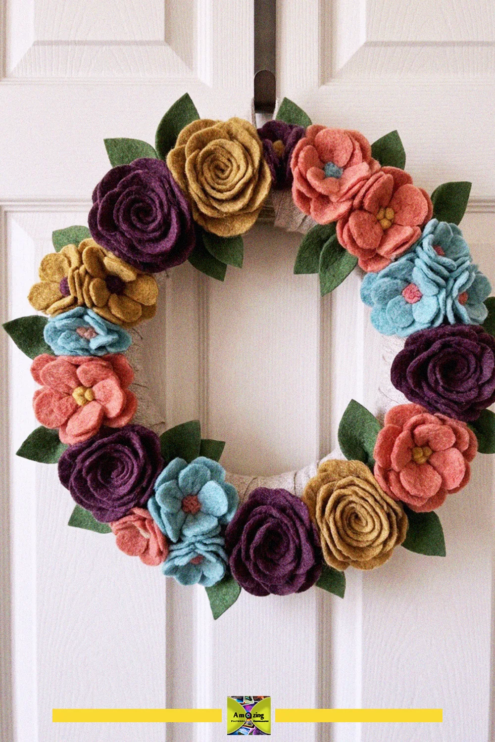 Colorful wreath of felted blanket-scrap flowers in rose, mustard and teal on a white door