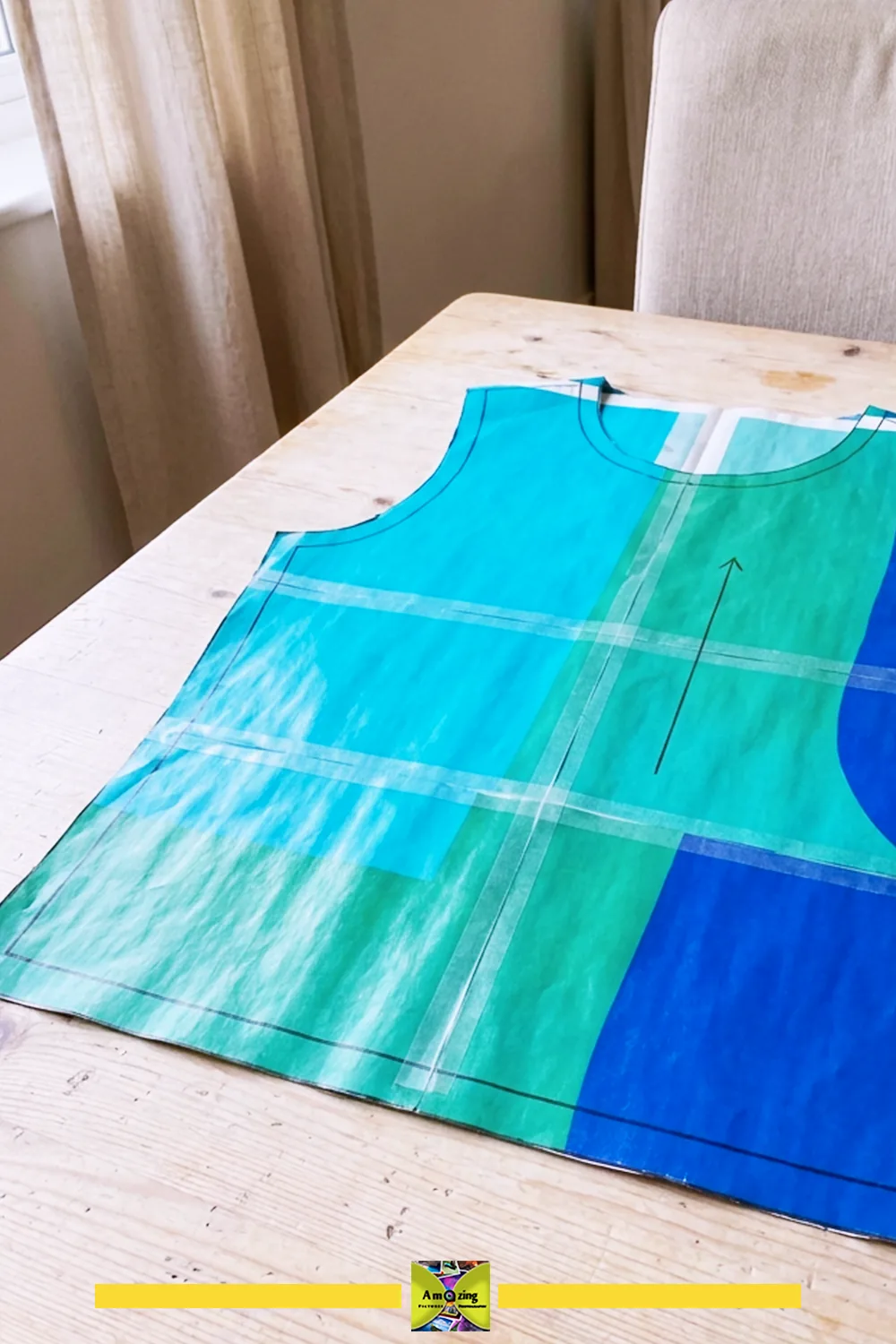 Large sewing pattern sheet with colorful markings taped to a wooden table