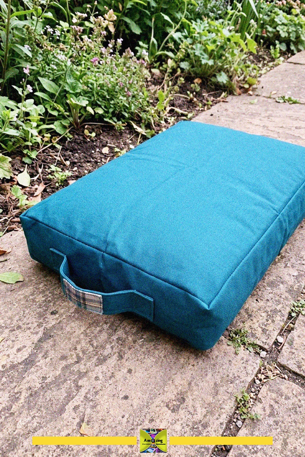 Blue garden kneeling cushion with a carry handle made from an upcycled blanket on a stone path
