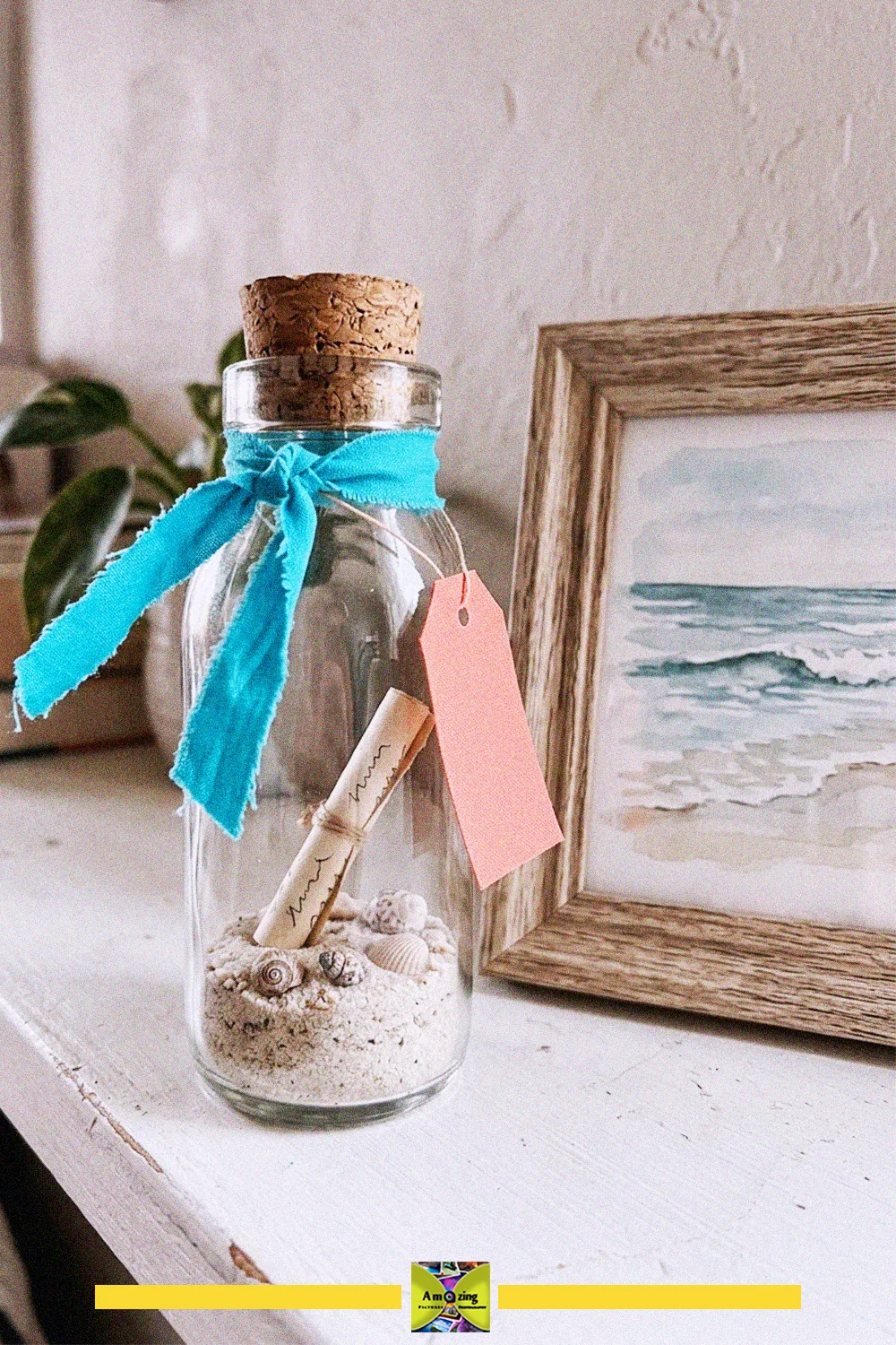 Upcycled glass bottle with a cork filled with sand, seashells and a rolled note, tied with a blue ribbon and tag
