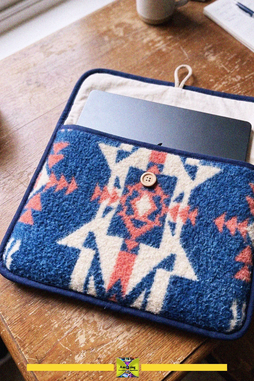 Blue and white geometric wool laptop sleeve made from a reused blanket on a wooden desk