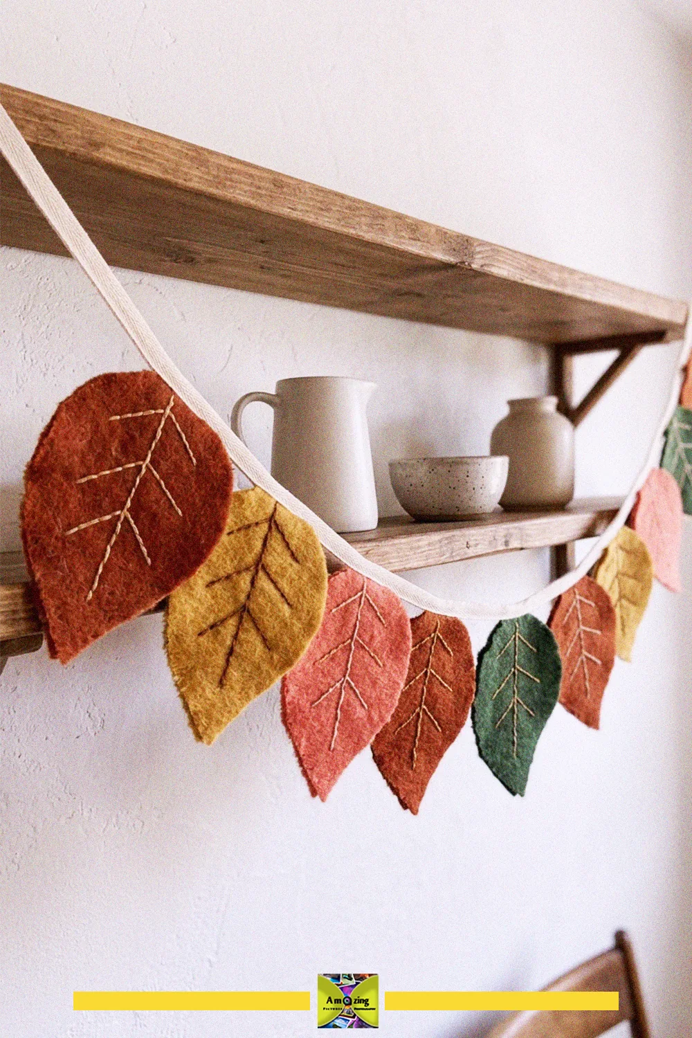 What to do with old blankets: a garland of felted blanket-scrap leaves in autumn colors hung on a shelf