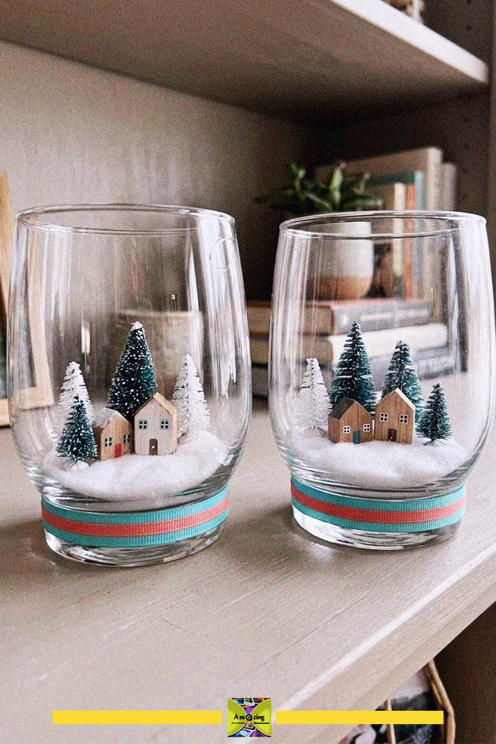 Two old glass cups holding miniature winter village scenes with tiny houses, bottle brush trees and faux snow