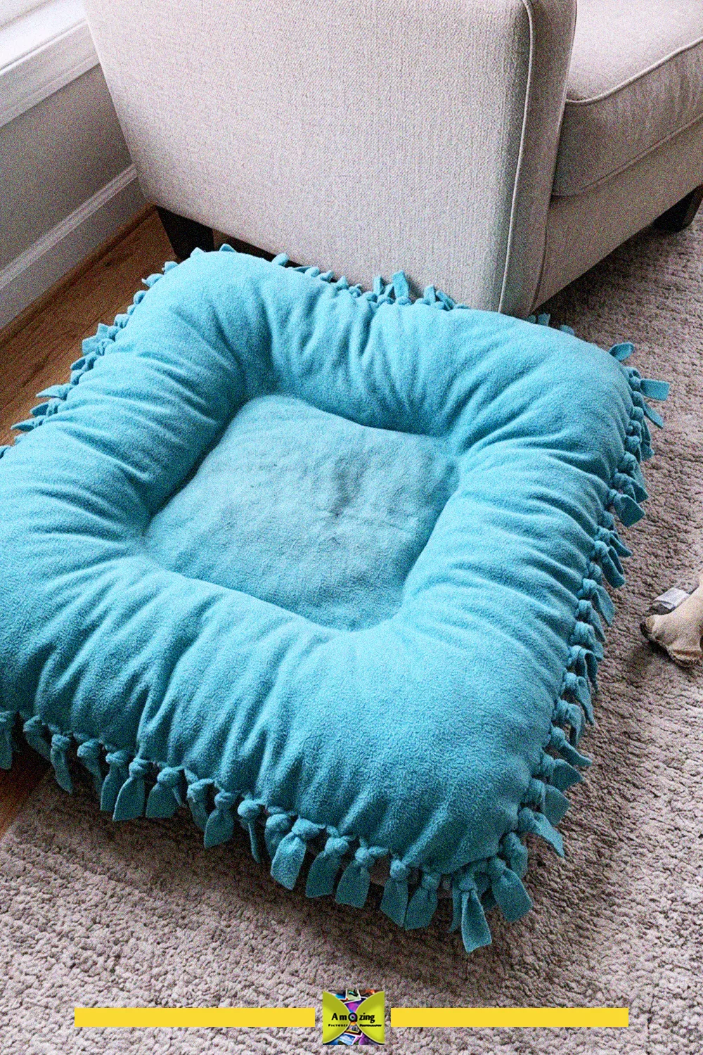 Turquoise no-sew pet bed made from an old fleece blanket with knotted fringe edges, on a carpet