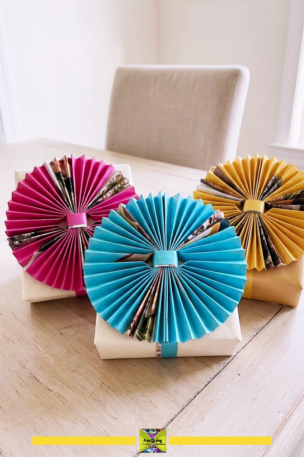 Three wrapped gifts decorated with colorful pleated magazine paper toppers on a wooden table.